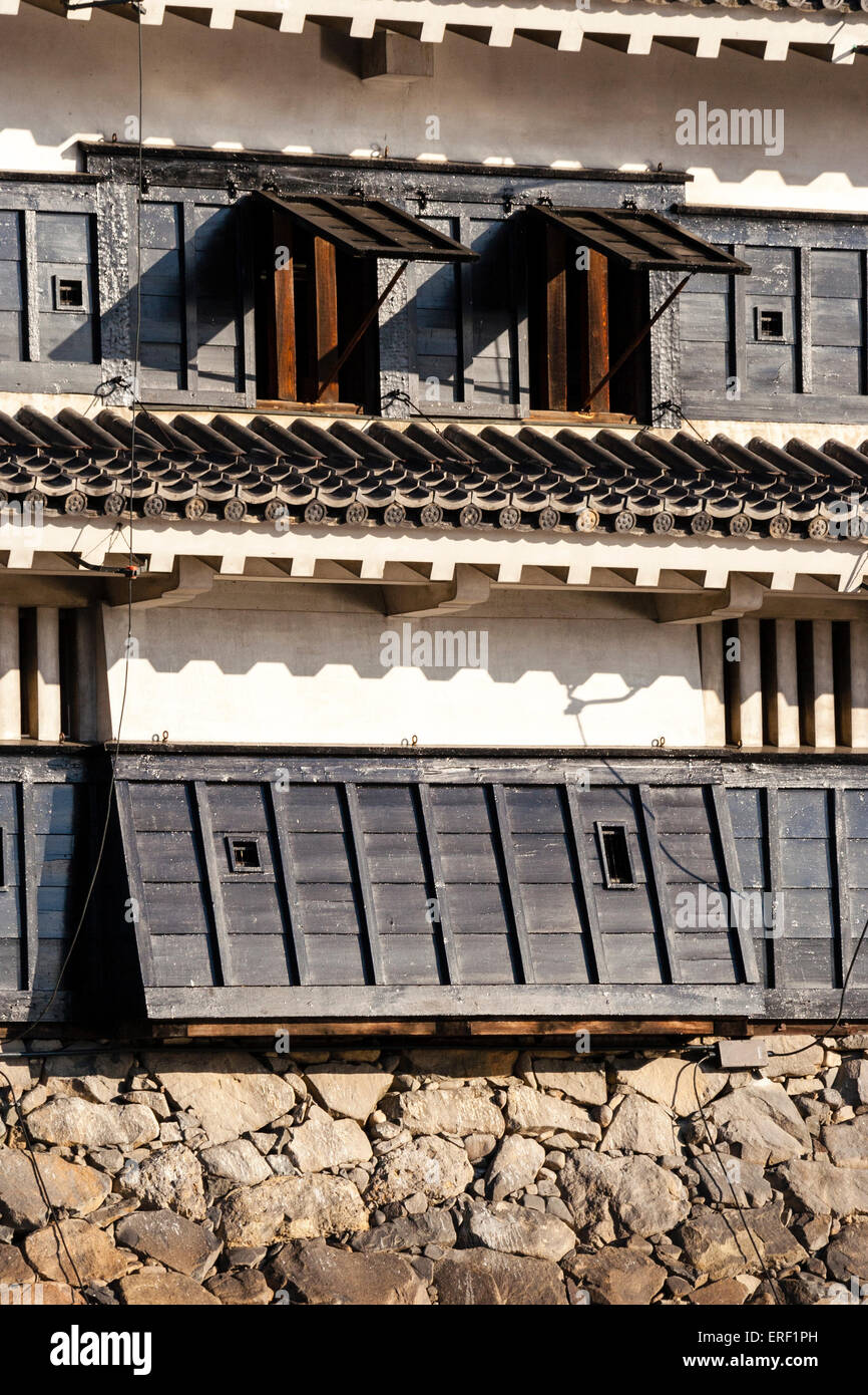 Primo piano, tenere del castello di Matsumoto, Giappone. Foro di caduta di pietra, ishi-otoshi, sopra la base di pietra e due porte-pistola finestra di otturatore e fessure. Foto Stock