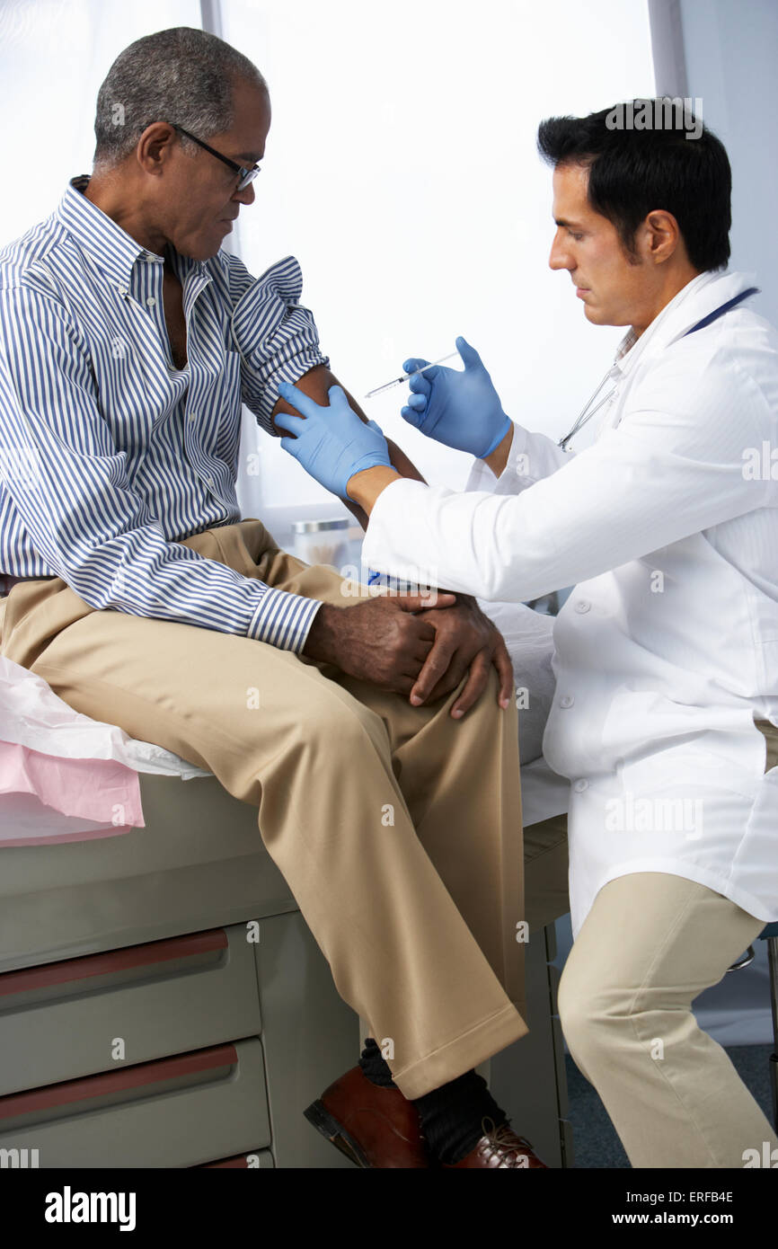 Dottore in chirurgia dando maschio iniezione del paziente Foto Stock