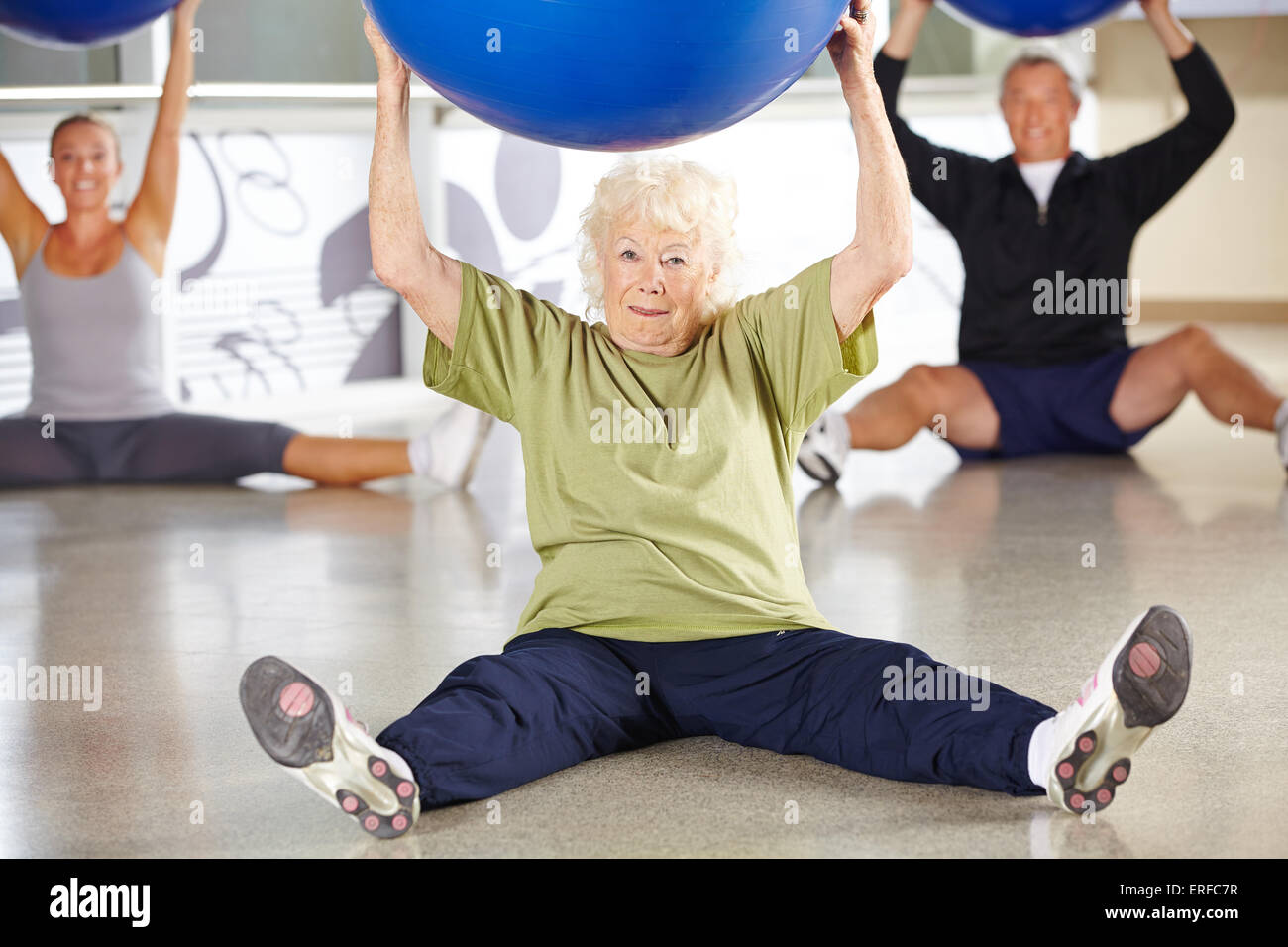 Senior donna facendo indietro traing con palla in un centro fitness Foto Stock
