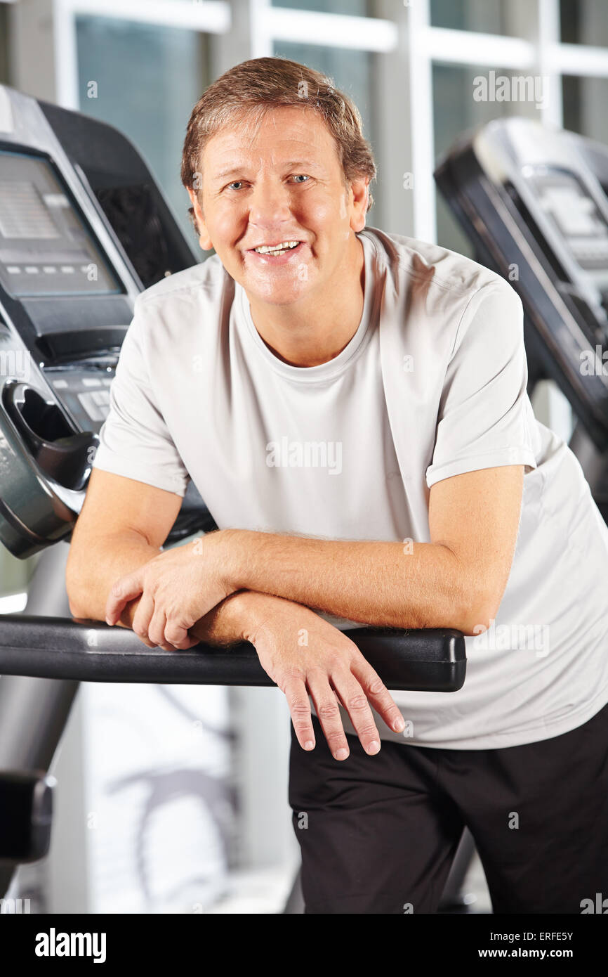 Attivo senior sorridente uomo sul tapis roulant nel centro fitness Foto Stock