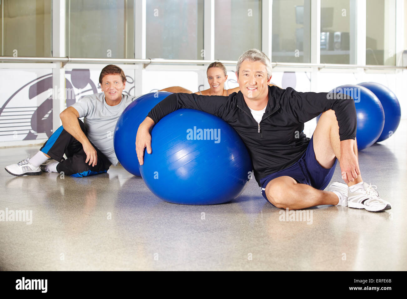 Uomo seduto in un gruppo di persone senior con palla in un centro fitness Foto Stock