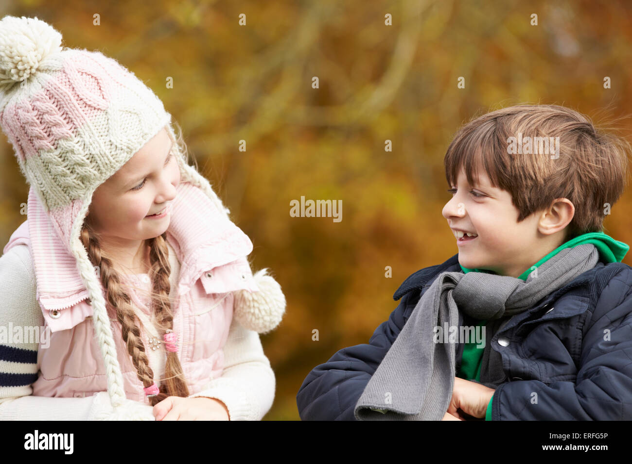 Due bambini Sporgendoti staccionata in legno a parlare Foto Stock
