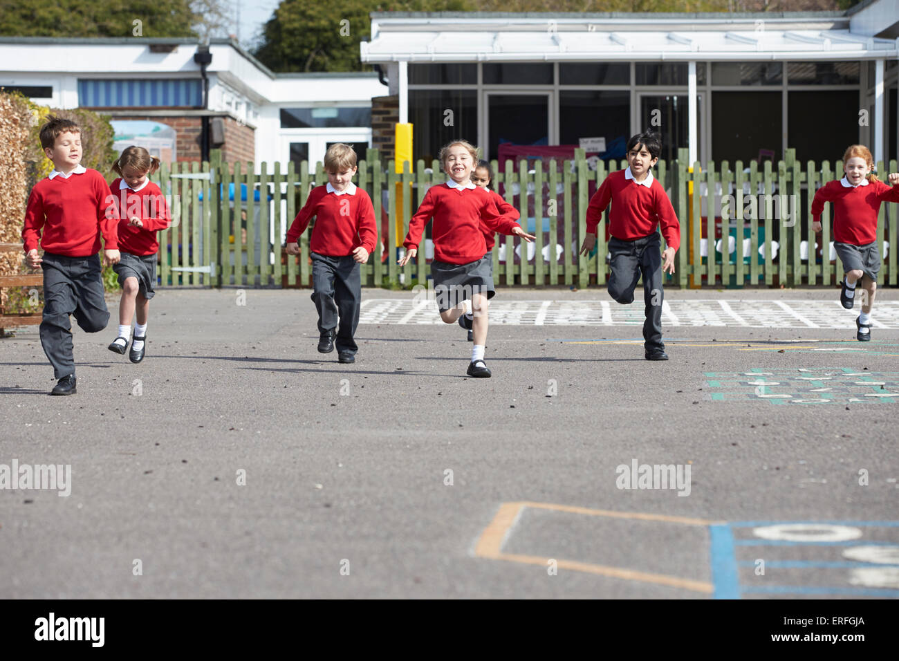 Scuola elementare di alunni in esecuzione nel parco giochi Foto Stock