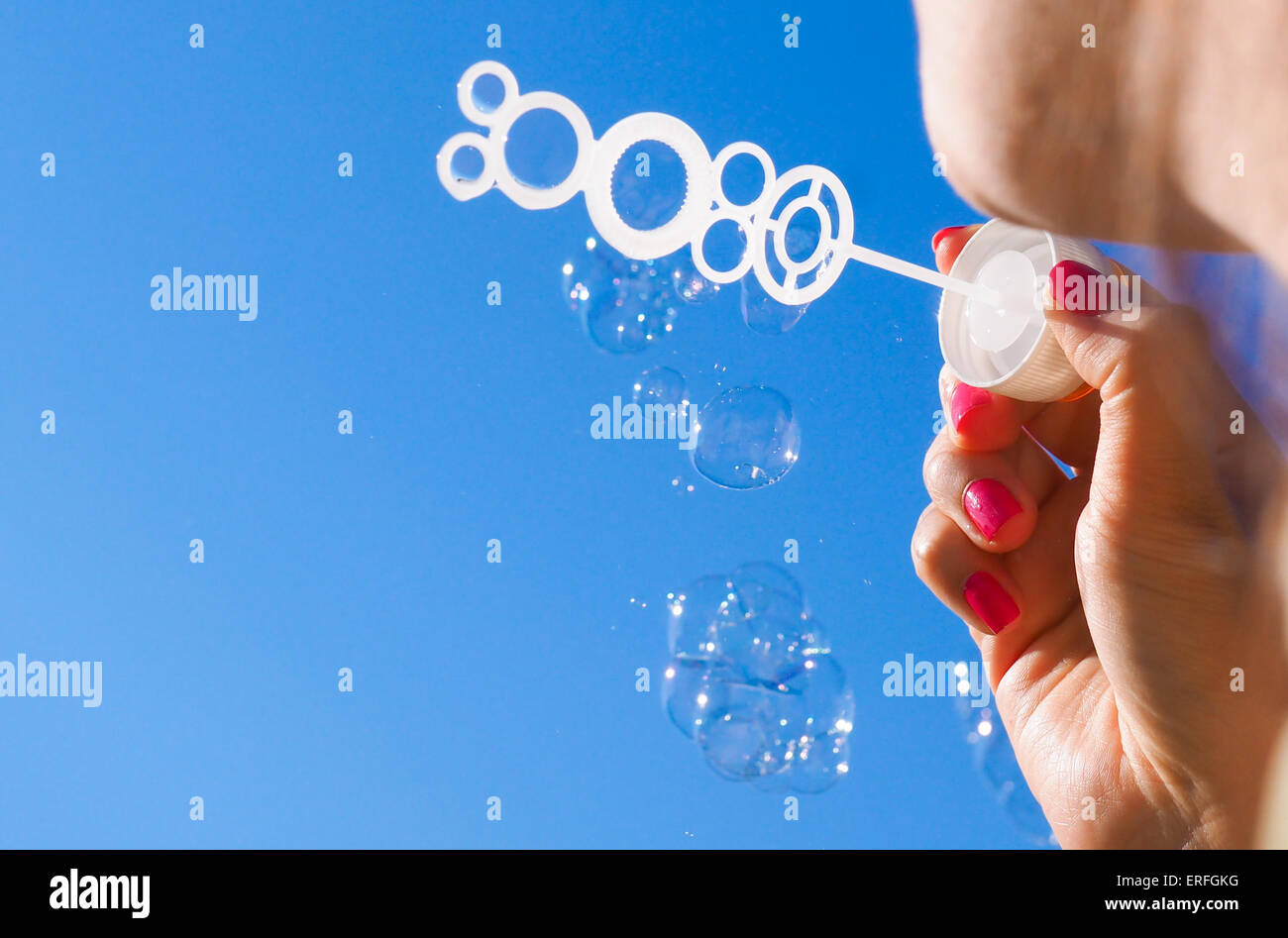 Persona di sesso femminile soffia bolle di sapone nel cielo blu Foto Stock
