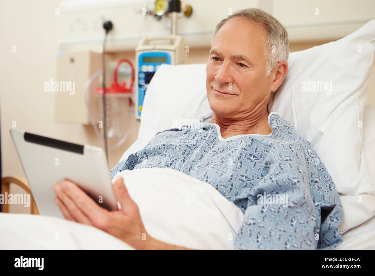 Senior paziente di sesso maschile con tavoletta digitale nel letto di ospedale Foto Stock