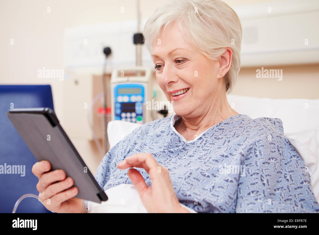 Senior paziente femmina con tavoletta digitale nel letto di ospedale Foto Stock