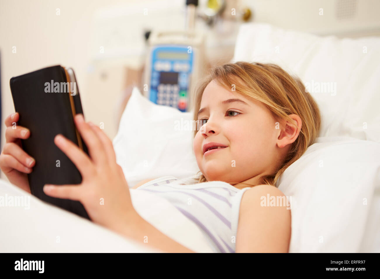 Giovani femmine paziente utilizzando digitale compressa nel letto di ospedale Foto Stock