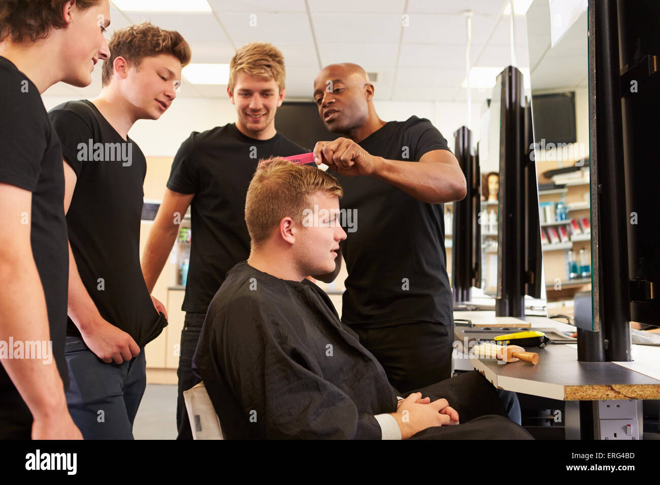 Insegnante aiuta gli studenti a formazione per diventare parrucchieri Foto Stock