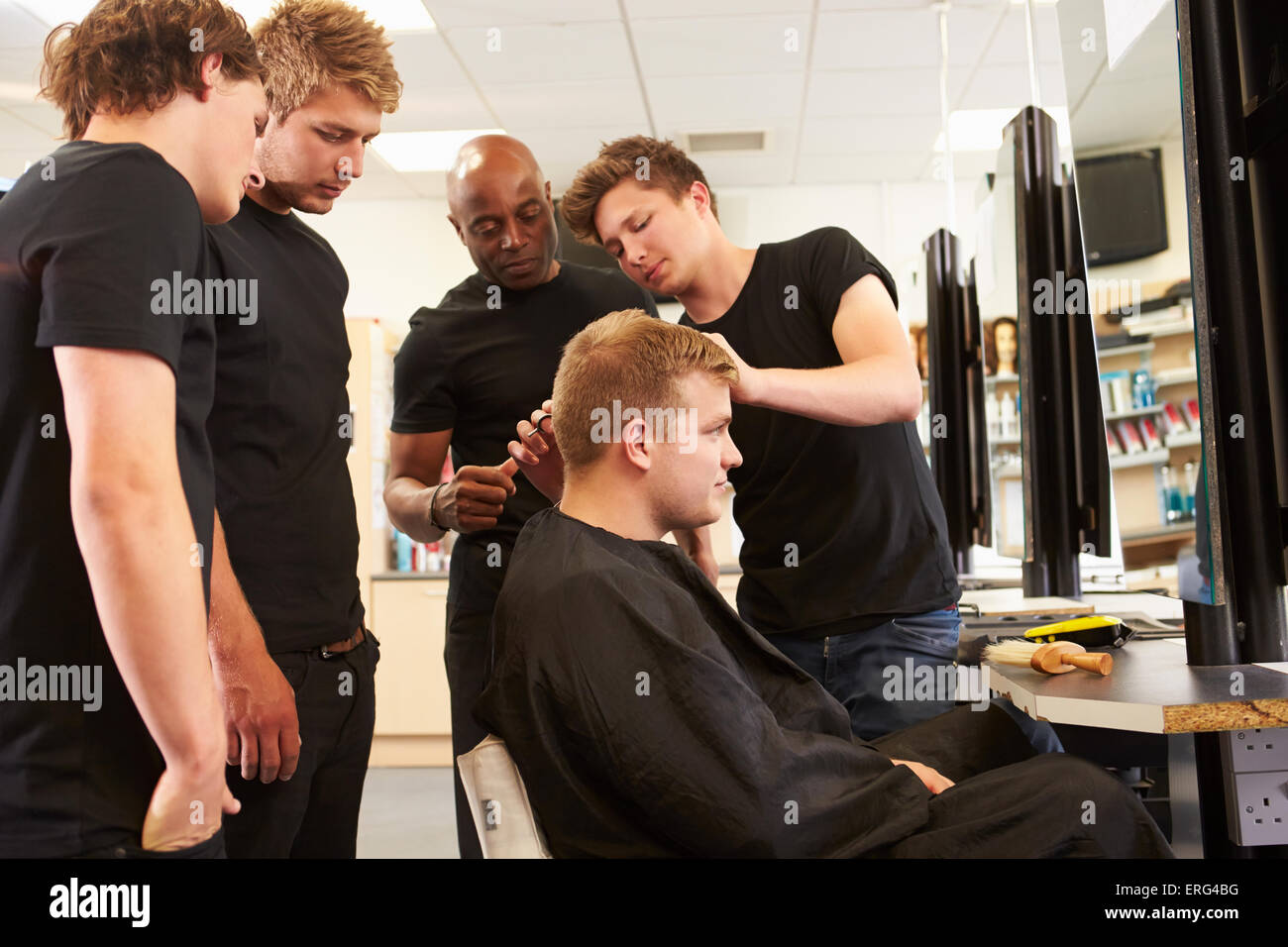 Insegnante aiuta gli studenti a formazione per diventare parrucchieri Foto Stock