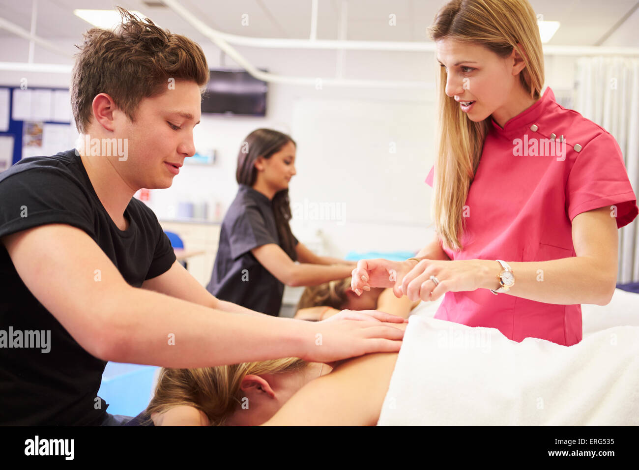 Insegnante contribuendo alla formazione degli studenti a diventare massaggiatrice Foto Stock