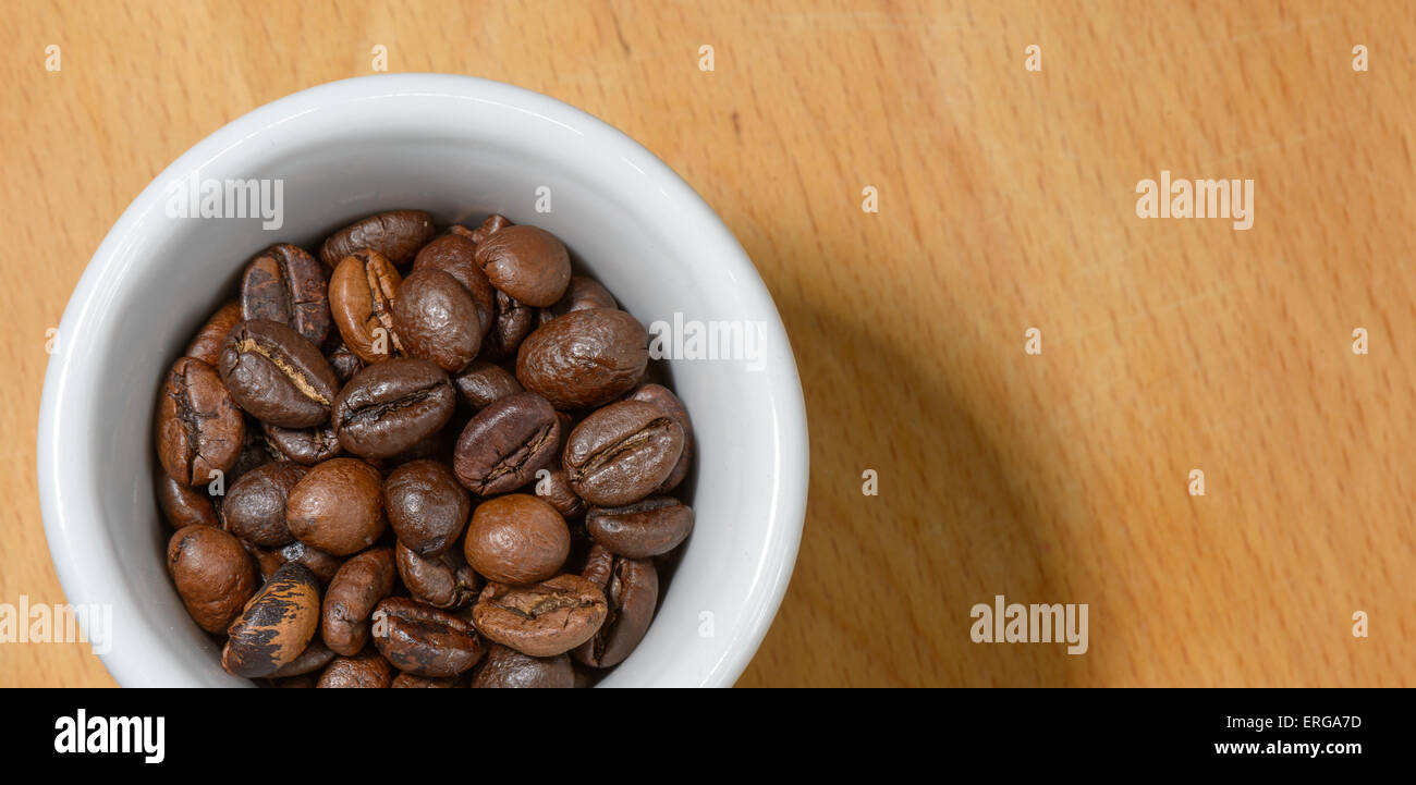 Bella tazza di caffè con caffè tostato semi interno su uno sfondo di legno Foto Stock