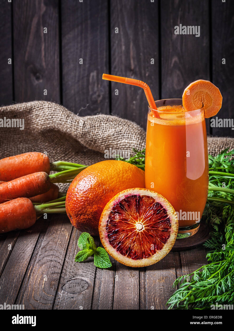 Succo di carota fresco arance in background in legno Foto Stock