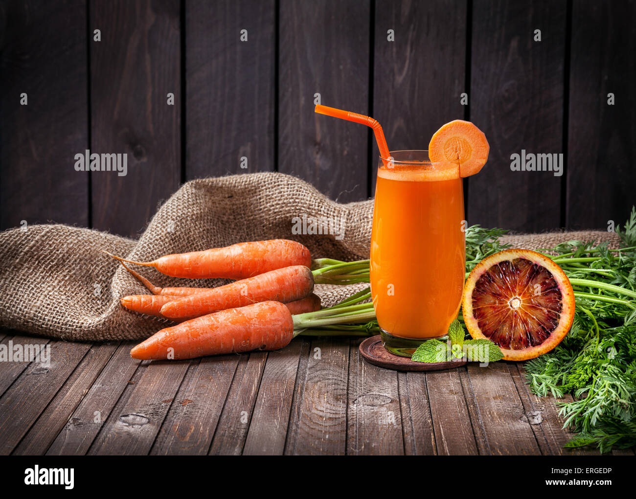 Carota fresco e succo di arancia con arance in background in legno Foto Stock