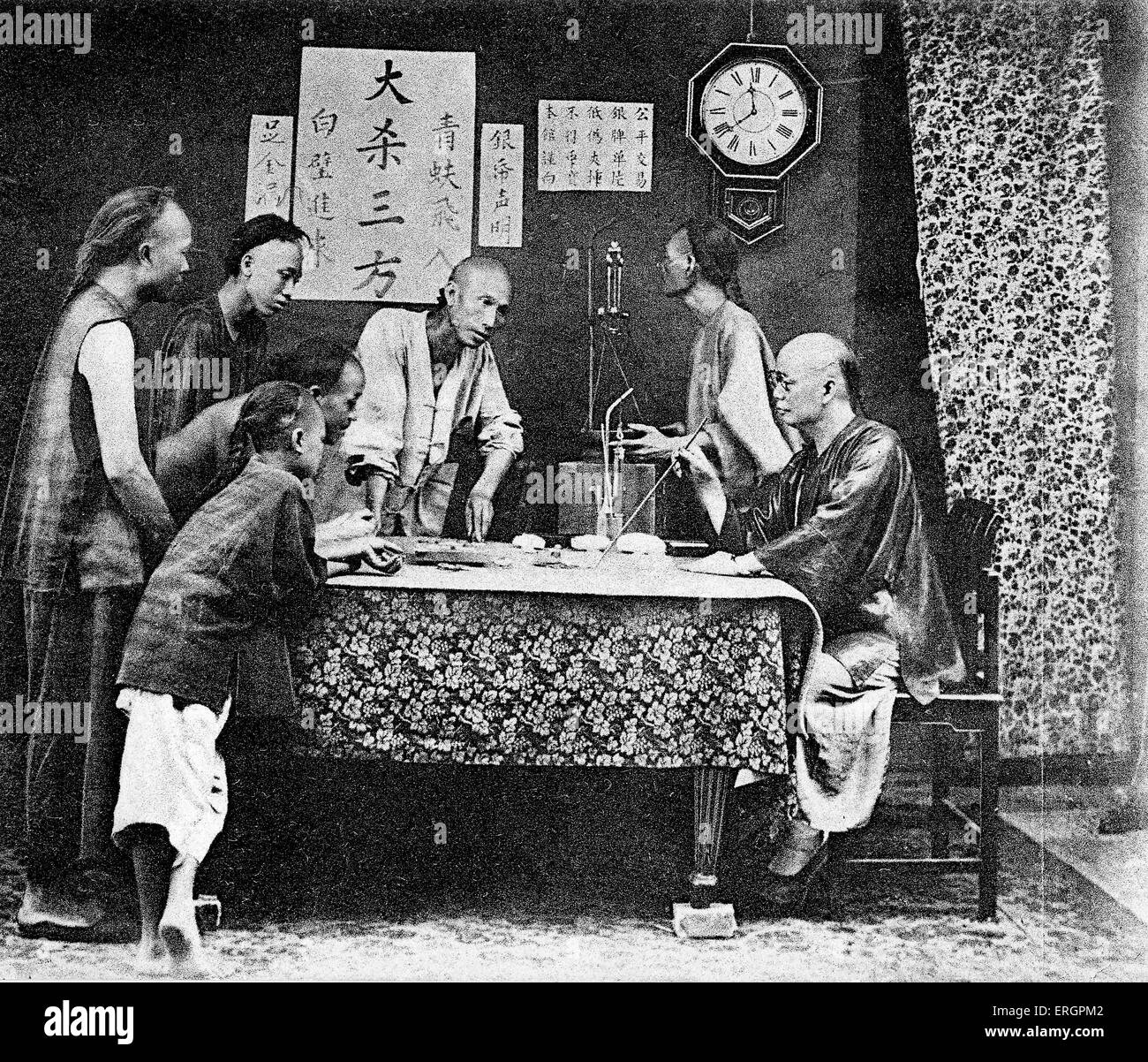 Gruppo di uomini giocando Fan-Tan, una forma di gioco d'azzardo. Nei primi anni del XX secolo. Cina, Hong Kong sotto amministrazione britannica. Foto Stock