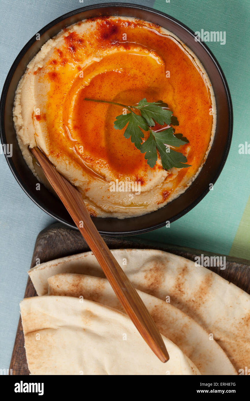 Una ciotola di hummus con olio d'oliva, pepe rosso e pane pita. Foto Stock