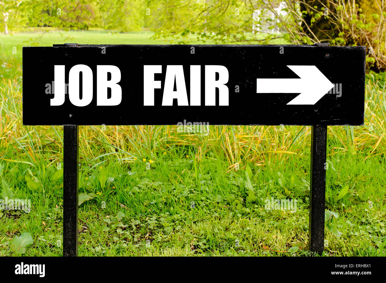 Fiera del lavoro scritto su direzionale di metallo nero a firmare con la freccia che punta a destra contro la naturale sfondo verde. Foto Stock