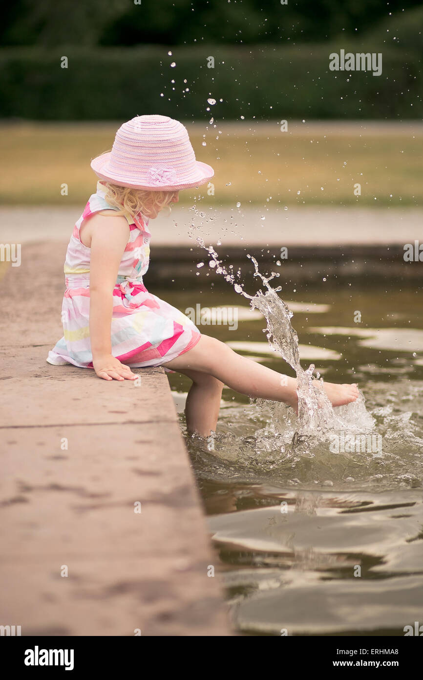 Ragazza spruzzi d'acqua con i suoi piedi Foto Stock