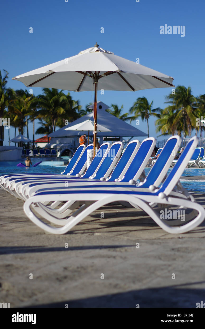 Sedie a sdraio attorno ad una piscina in un resort tropicale Foto Stock