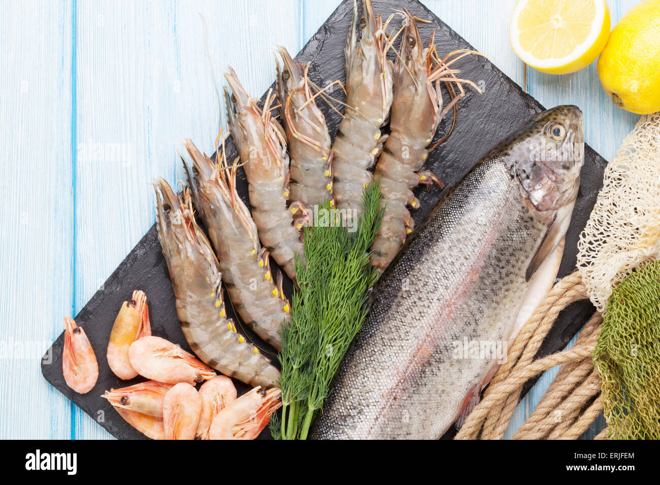 Crudo fresco il cibo del mare con spezie sulla lastra di pietra su un tavolo di legno dello sfondo. Vista superiore Foto Stock