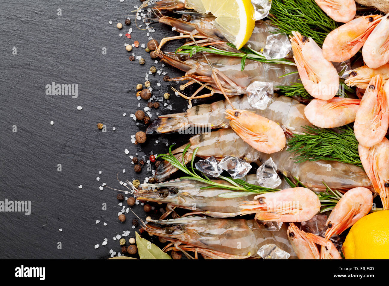 Gamberetti freschi con spezie sulla pietra nera dello sfondo. Vista da sopra con lo spazio di copia Foto Stock