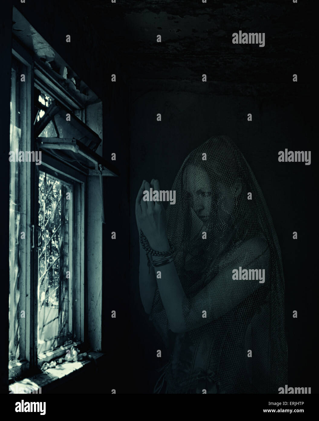 Halloween scene di orrore. Triste scary trasparente donna blured ghost pregando sulla finestra nella vecchia casa Foto Stock