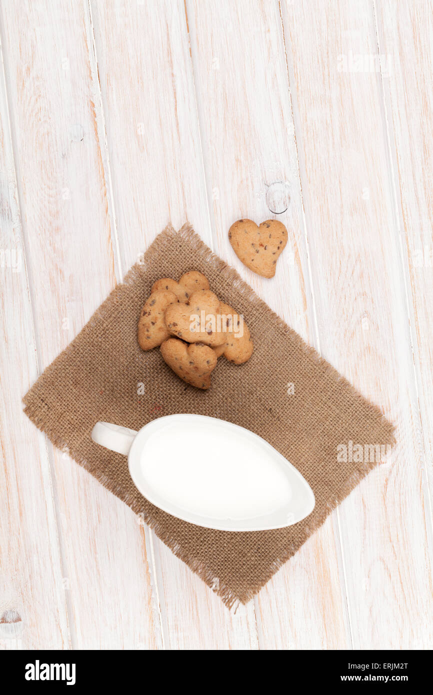 A forma di cuore ad gingerbread cookie e la brocca del latte. Su bianco tavolo in legno Foto Stock