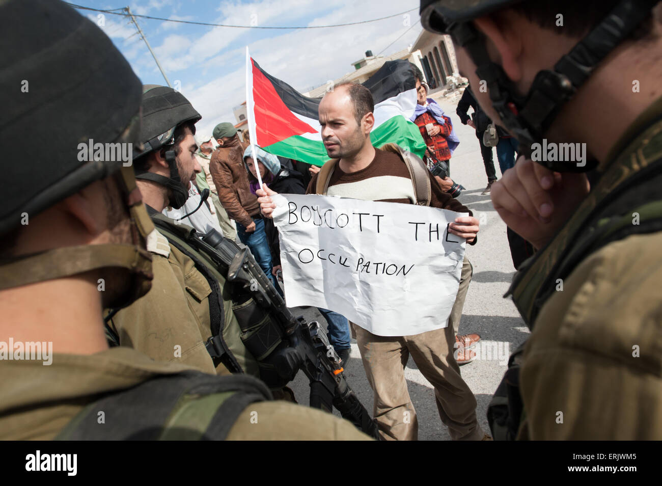 Un attivista palestinese con un segno di lettura, "boicottare l'occupazione, volti soldati israeliani durante una manifestazione di protesta nella West Bank. Foto Stock