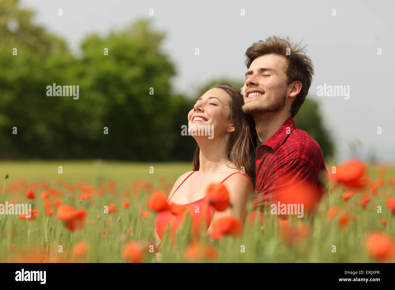 Coppia romantica avvolgente e di respirare aria fresca in un campo caldo con fiori di colore rosso Foto Stock