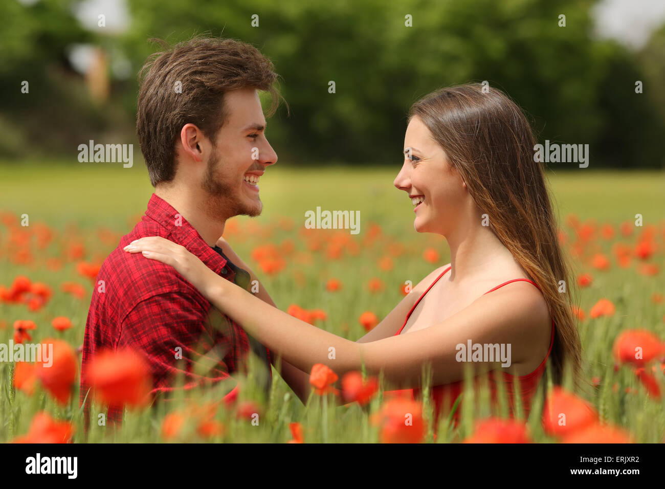 Coppia felice cercando ogni altro affettuoso in un campo con papavero rosso fiori Foto Stock