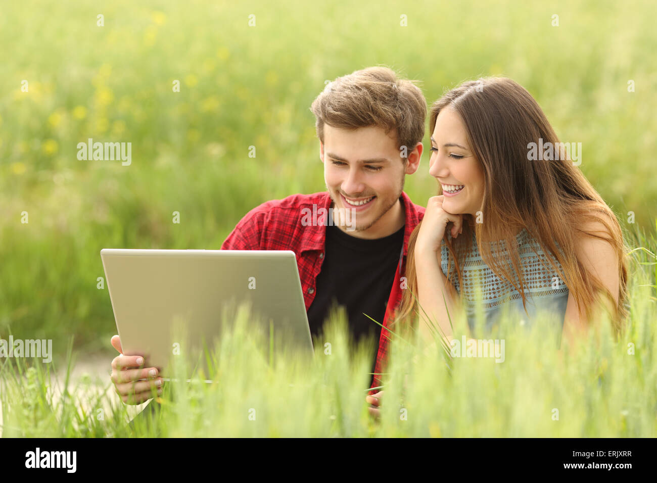 Coppia o amici la condivisione di un computer portatile in un campo verde Foto Stock