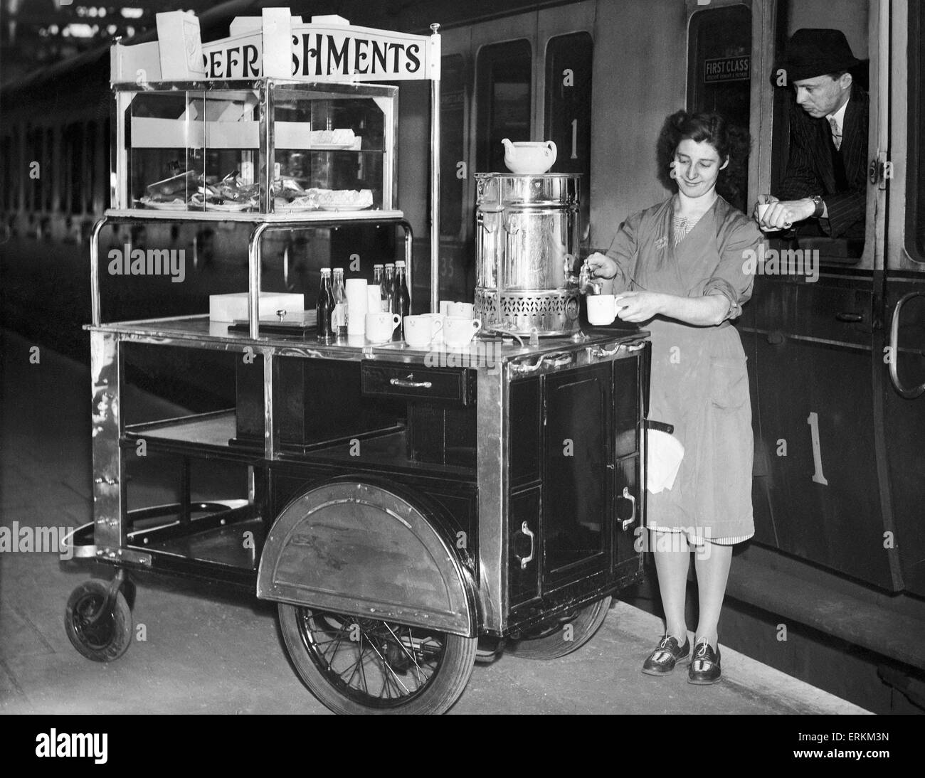 Un lavoratore di sesso femminile che a Snow Hill la stazione ferroviaria di Birmingham serve una tazza di tè da lei rinfreschi trolley per un passeggero in corrispondenza della finestra del suo treno carrello, introdotto dalla regione occidentale delle ferrovie britanniche. Il 31 maggio 1949. Foto Stock