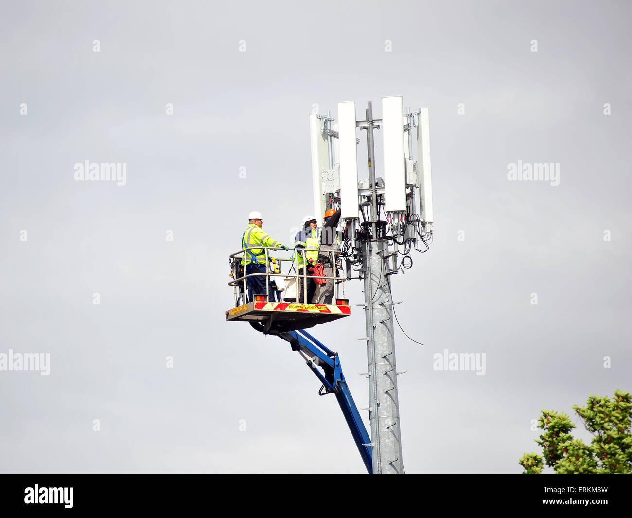 Operai effettuare riparazioni sul montante di telecomunicazione utilizzando una gru mobile. Foto Stock
