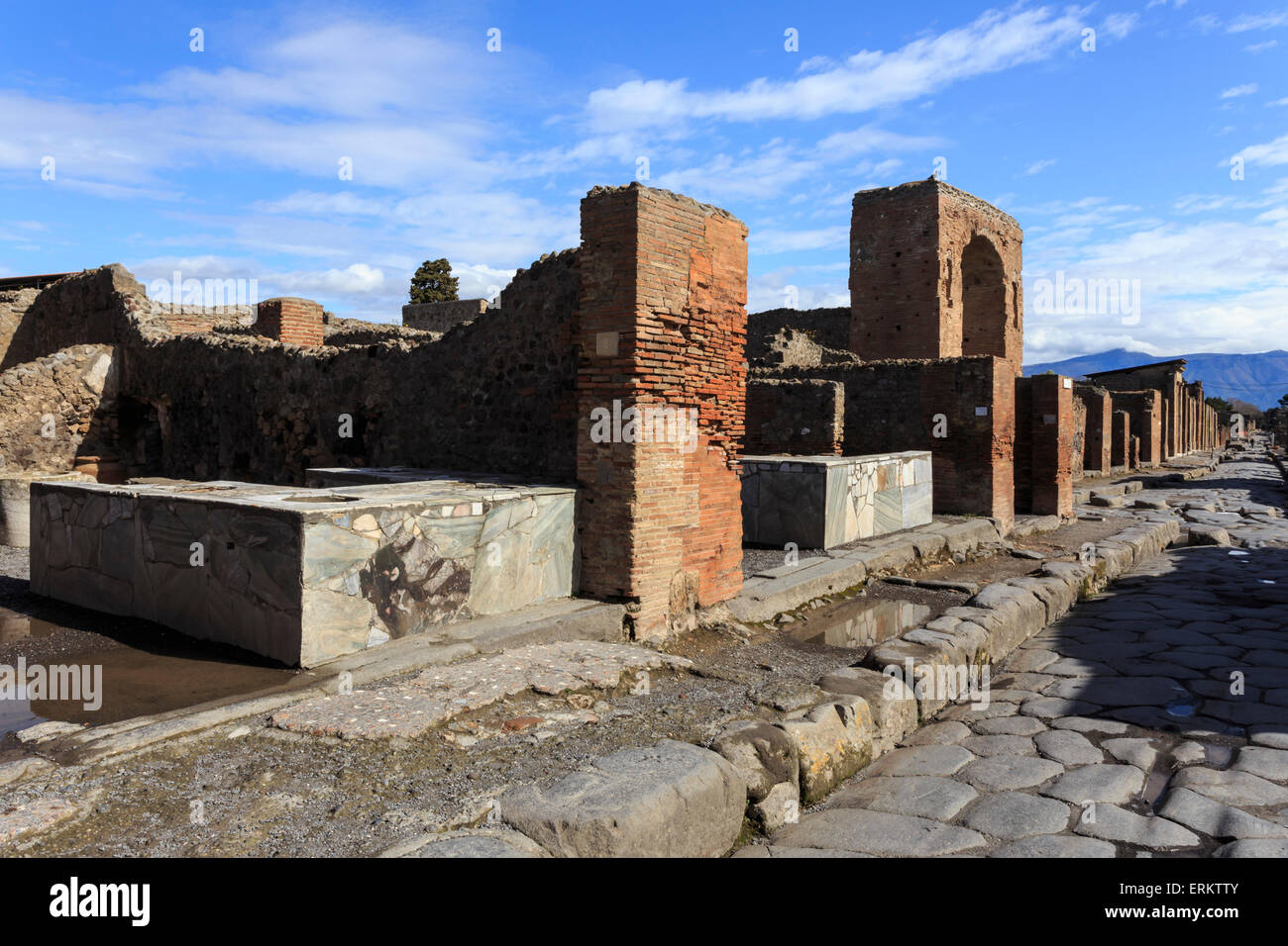 Strada di ciottoli con thermopolium contatori e arch, le rovine romane di Pompei, Sito Patrimonio Mondiale dell'UNESCO, Campania, Italia, Europa Foto Stock