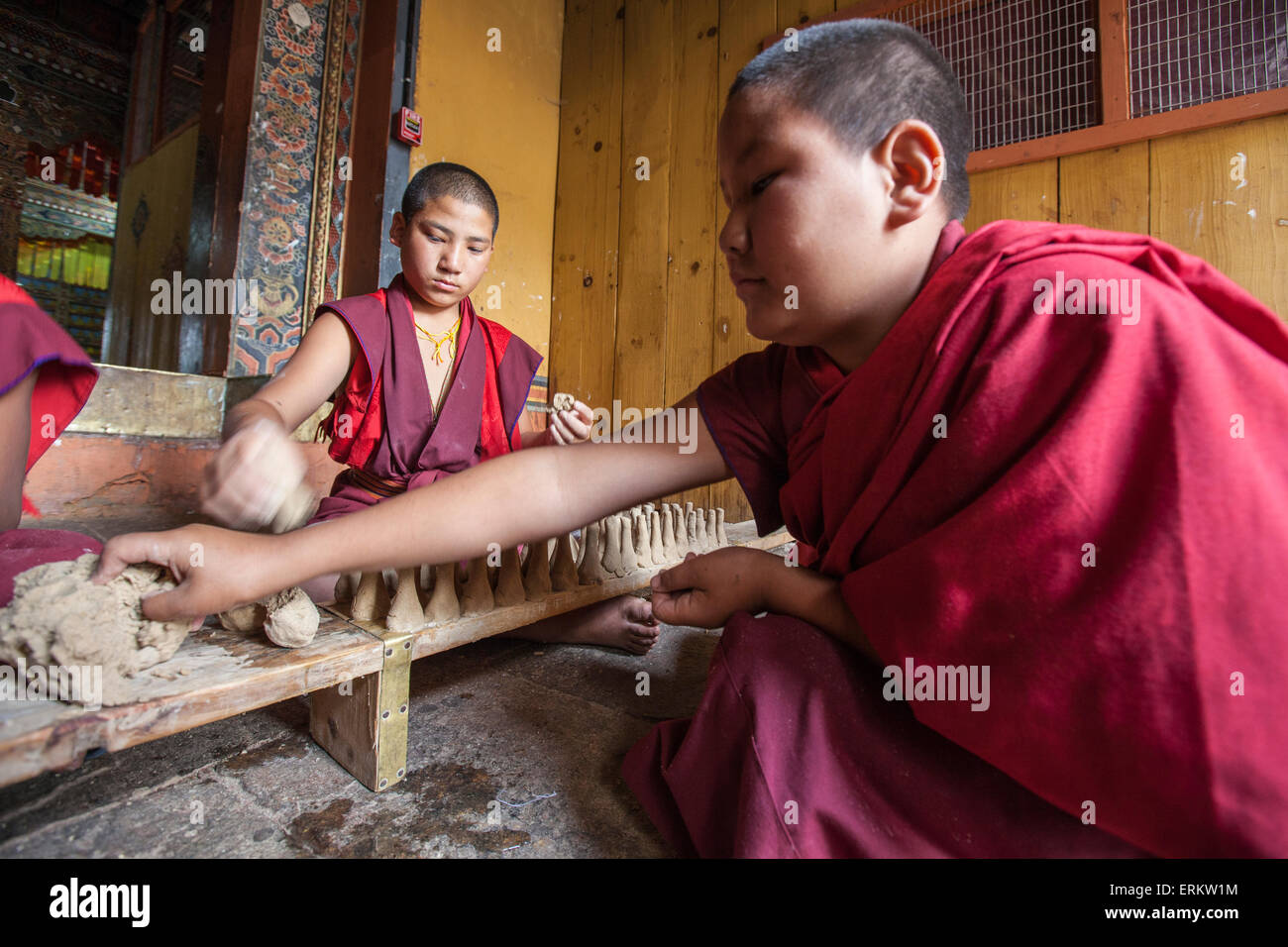 Giovane monaco buddista prende creta con la sua mano per creare oggetti che saranno venduti, Punakha, Bhutan Foto Stock