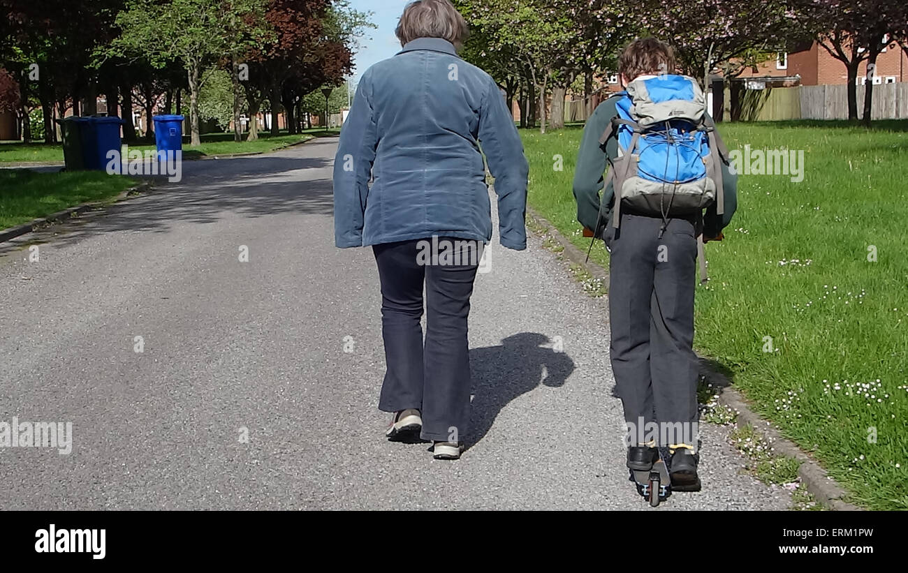 Ragazzo giovane andando a scuola su uno scooter con la nonna Foto Stock