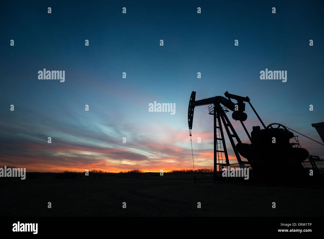 Un pumpjack a un olio sito di perforazione al tramonto. Foto Stock