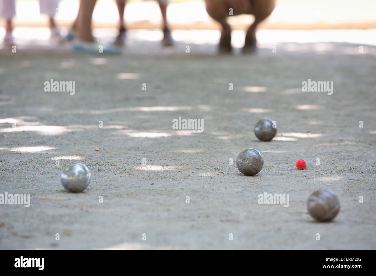 Un gioco di bocce in corso sul terreno sabbioso in ombra. Foto Stock