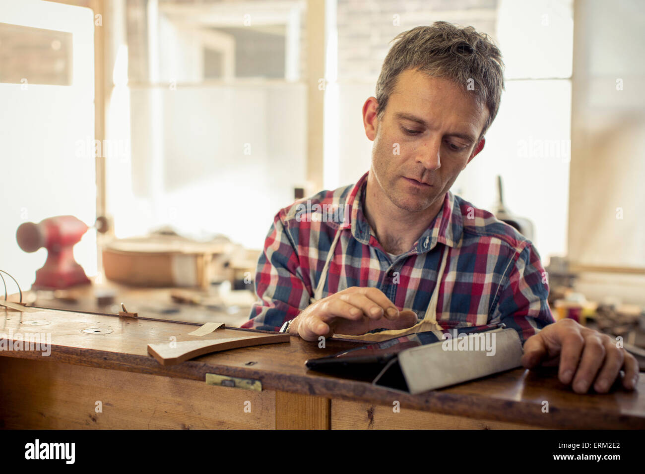 Un arredamento antico restauratore, un artigiano utilizzando una tavoletta digitale nel corso del suo lavoro. Foto Stock