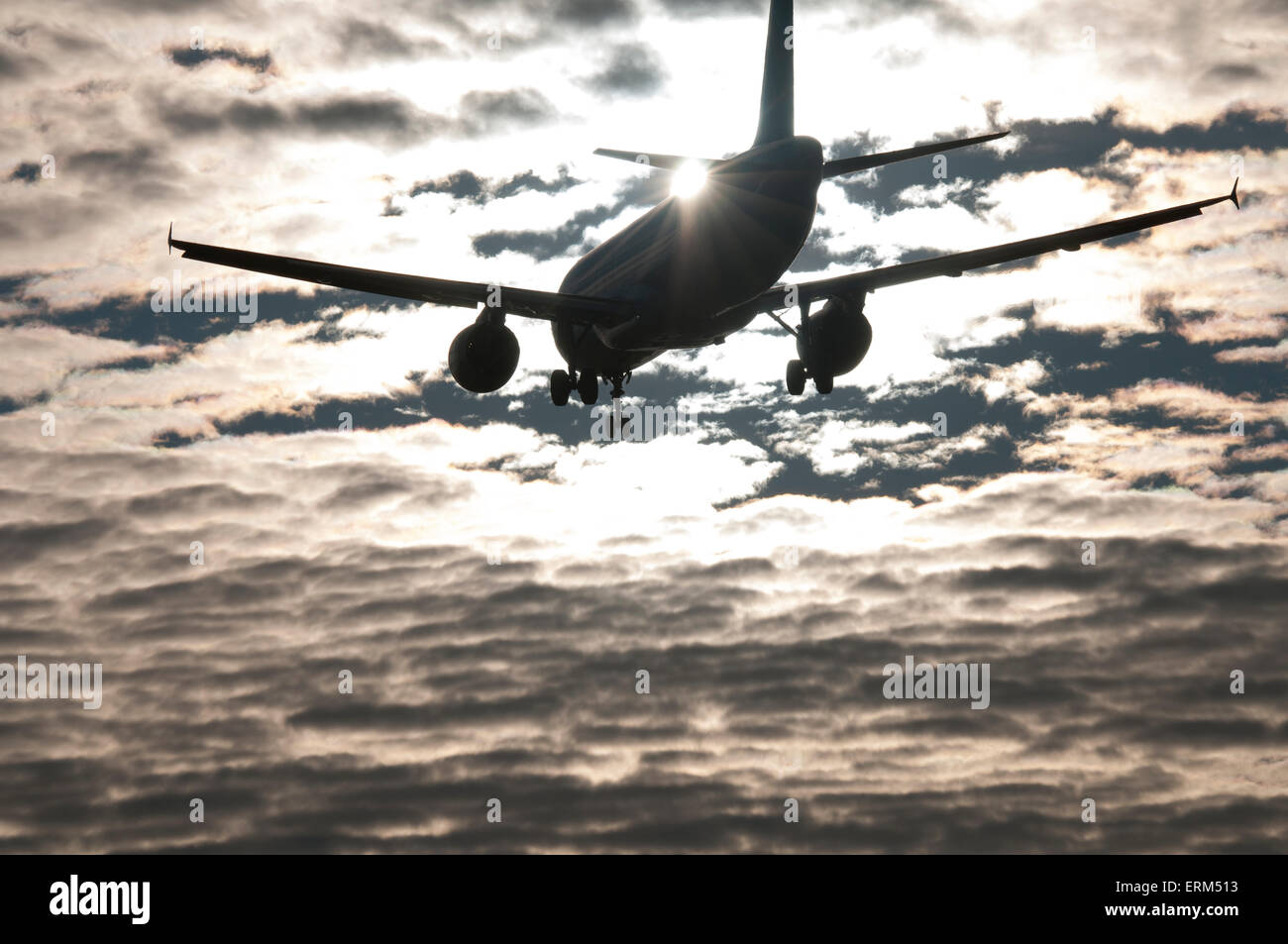 Aviogetti sull approccio finale, in silhouette con sfondo di dispersione e cloud computing Sun dietro la coda di aeromobili Foto Stock