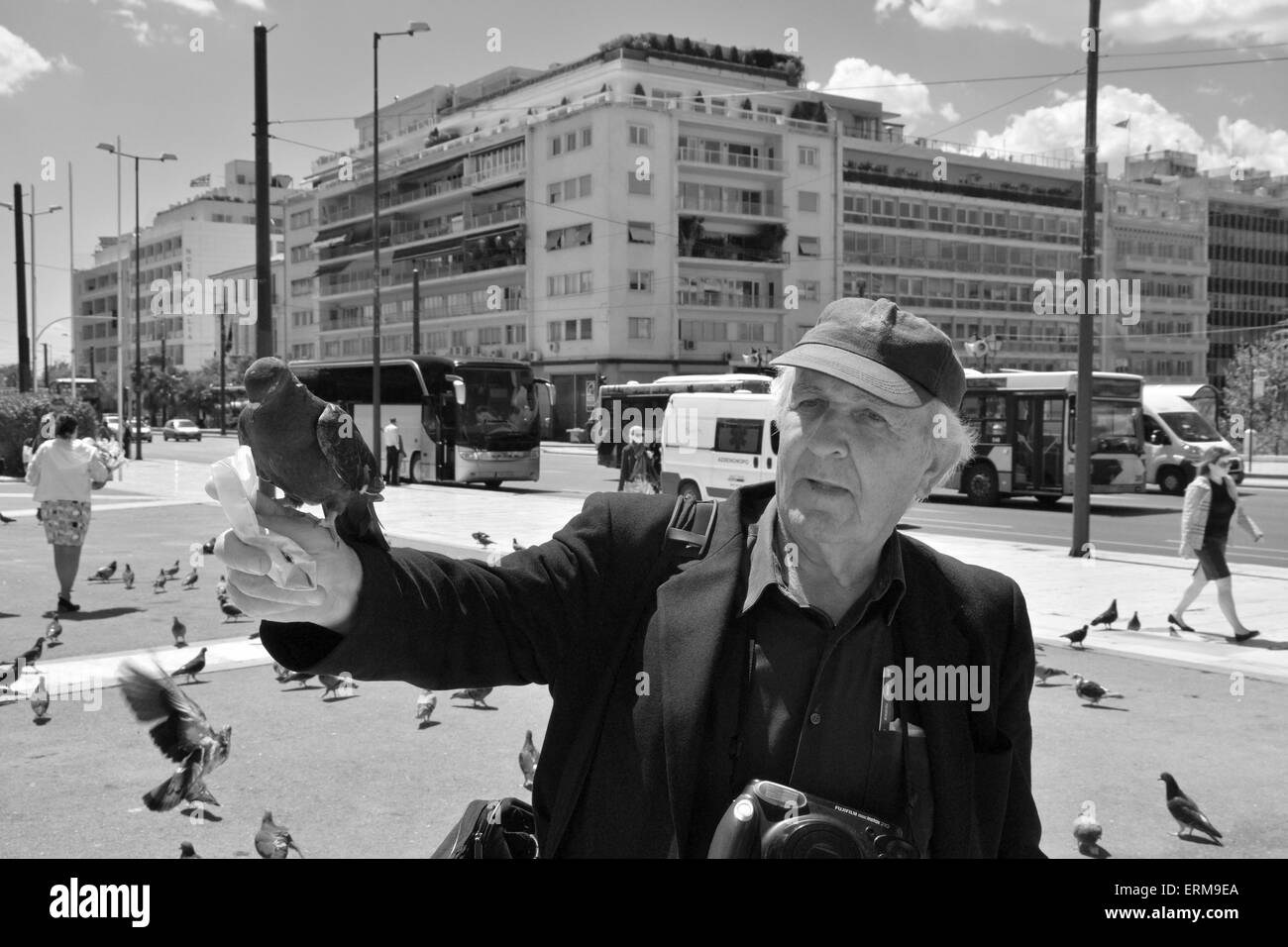 L'uomo alimentazione dei piccioni e di persone a piedi a piazza Syntagma nel centro di Atene, Grecia. Foto Stock