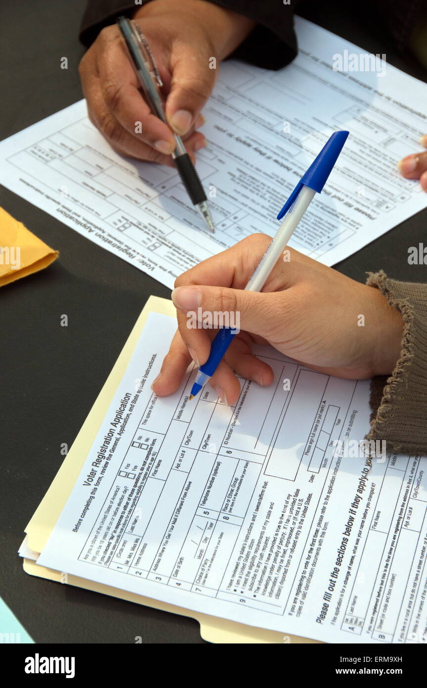 Due individui, entrambi con una penna in mano, completano la loro domanda individuale di registrazione Voter Stati Uniti durante una campagna per firmare nuovi elettori. Foto Stock