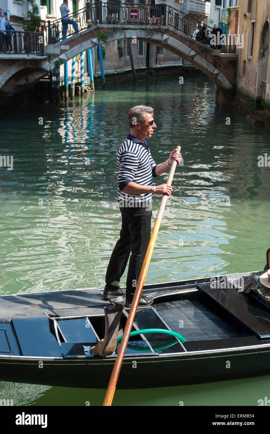 Venezia, Italia - 24 Aprile 2013: gondoliere veneziano sterline la sua gondola lungo le acque verdi di un canale. Foto Stock