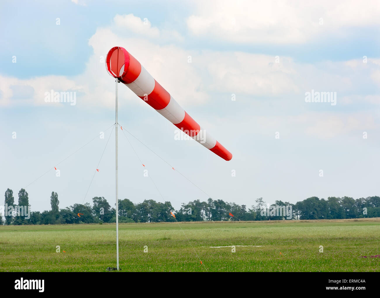 Manica a vento contro il cielo nuvoloso. L'aviosuperficie con erba verde. Foto Stock