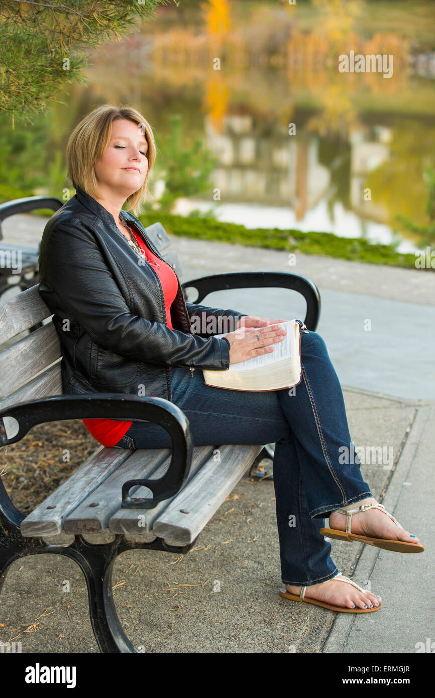 Coppia donna cristiana studiando la sua Bibbia in un parco della città impostazione accanto a un lago; Edmonton, Alberta, Canada Foto Stock