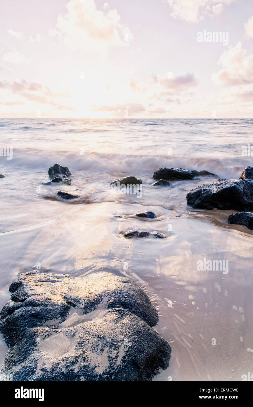 Spruzzi di surf sulle rocce dopo l'alba; Wailua, Kauai, Hawaii, Stati Uniti d'America Foto Stock