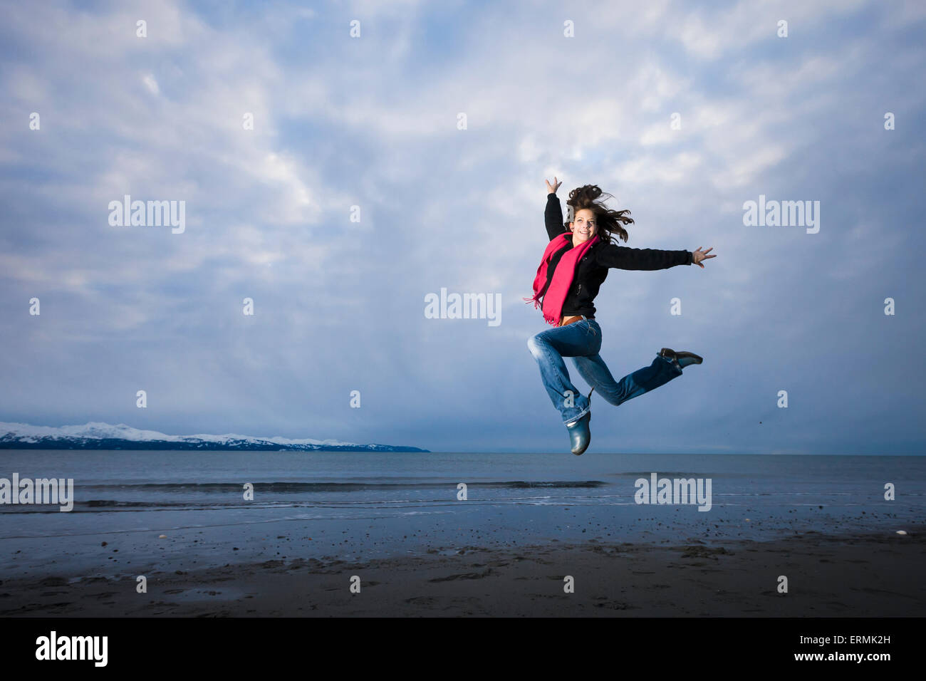 Giovane donna giocando e saltando su Homer Spit, Penisola di Kenai, centromeridionale Alaska Foto Stock