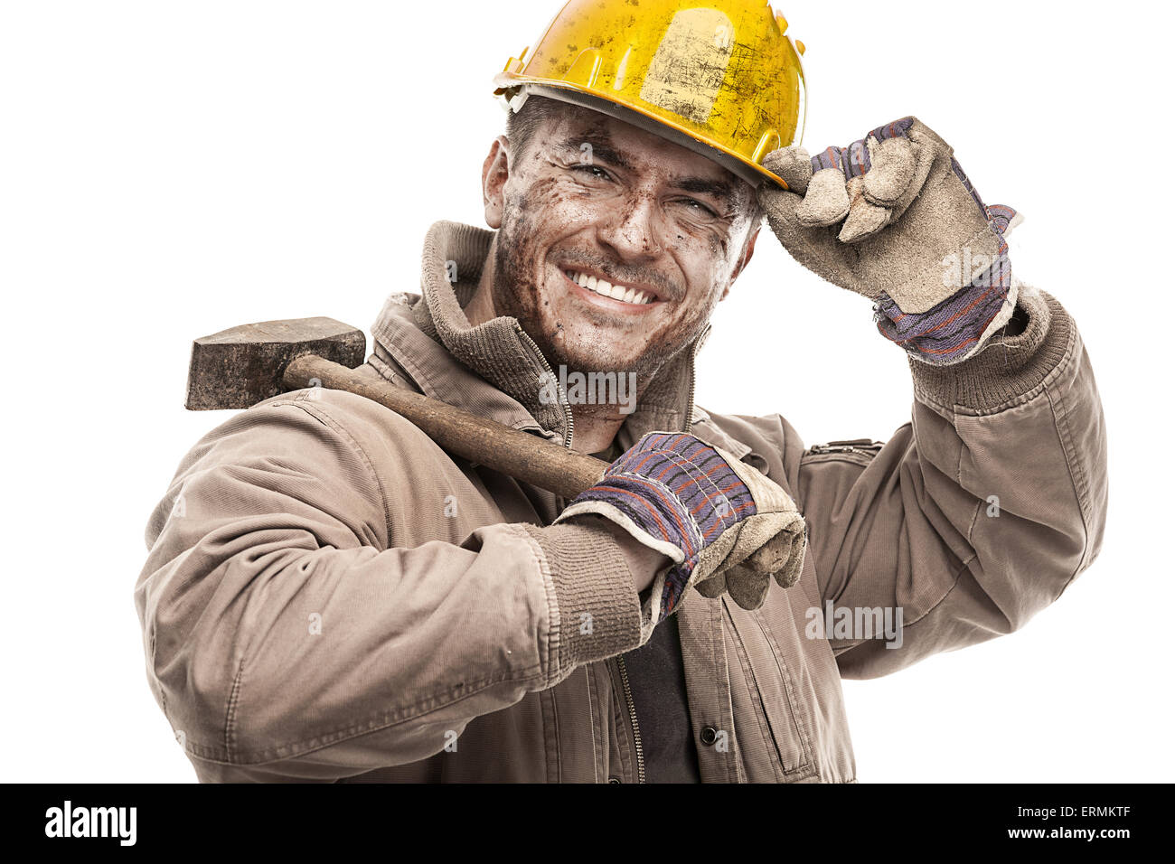 Giovane lavoratore sporco uomo con elmetto casco tenendo un martello e sorridente isolati su sfondo bianco Foto Stock