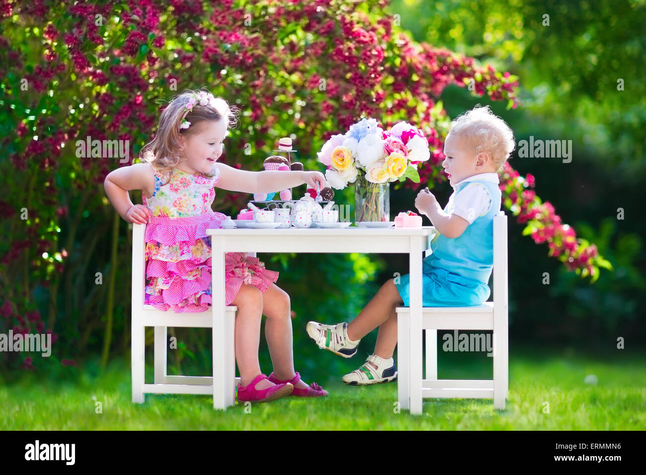 Tea party in giardino per bambini. Bambino celebrazione di compleanno. Piccolo Ragazzo e ragazza giocare all'aperto a bere cioccolata calda e mangiare la torta. Foto Stock