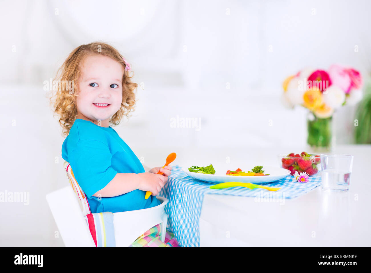 Felice bambina carina toddler ricci, mangiare verdura fresca per il pranzo, insalata di sani snack, mais, broccoli, carote e frutta Foto Stock