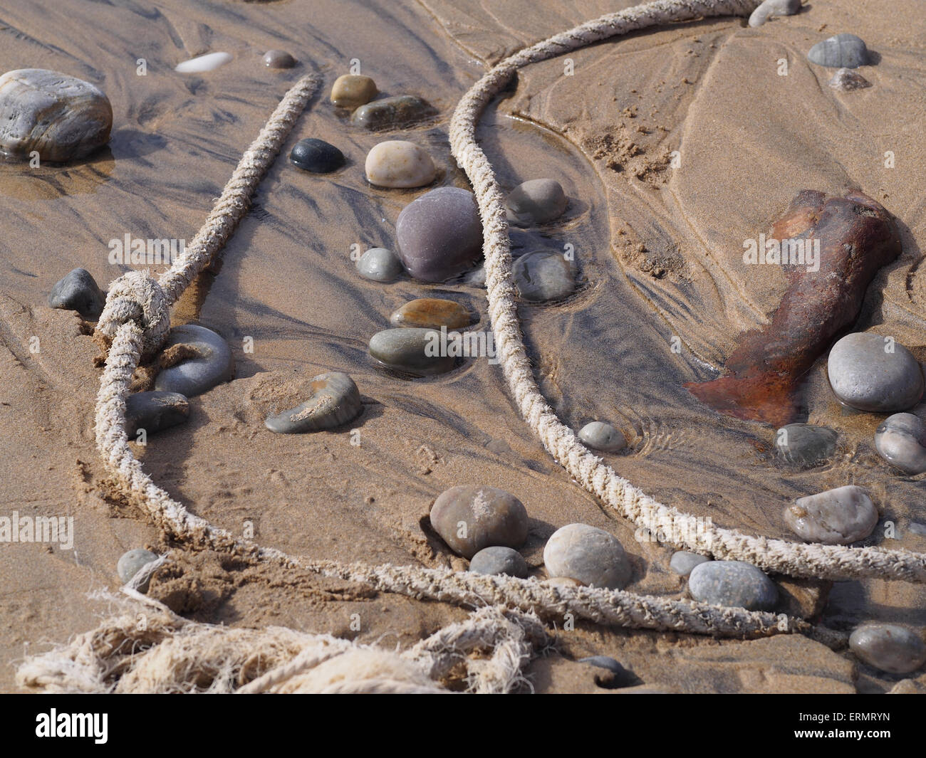 Deviati corda e pietre sulla spiaggia Foto Stock